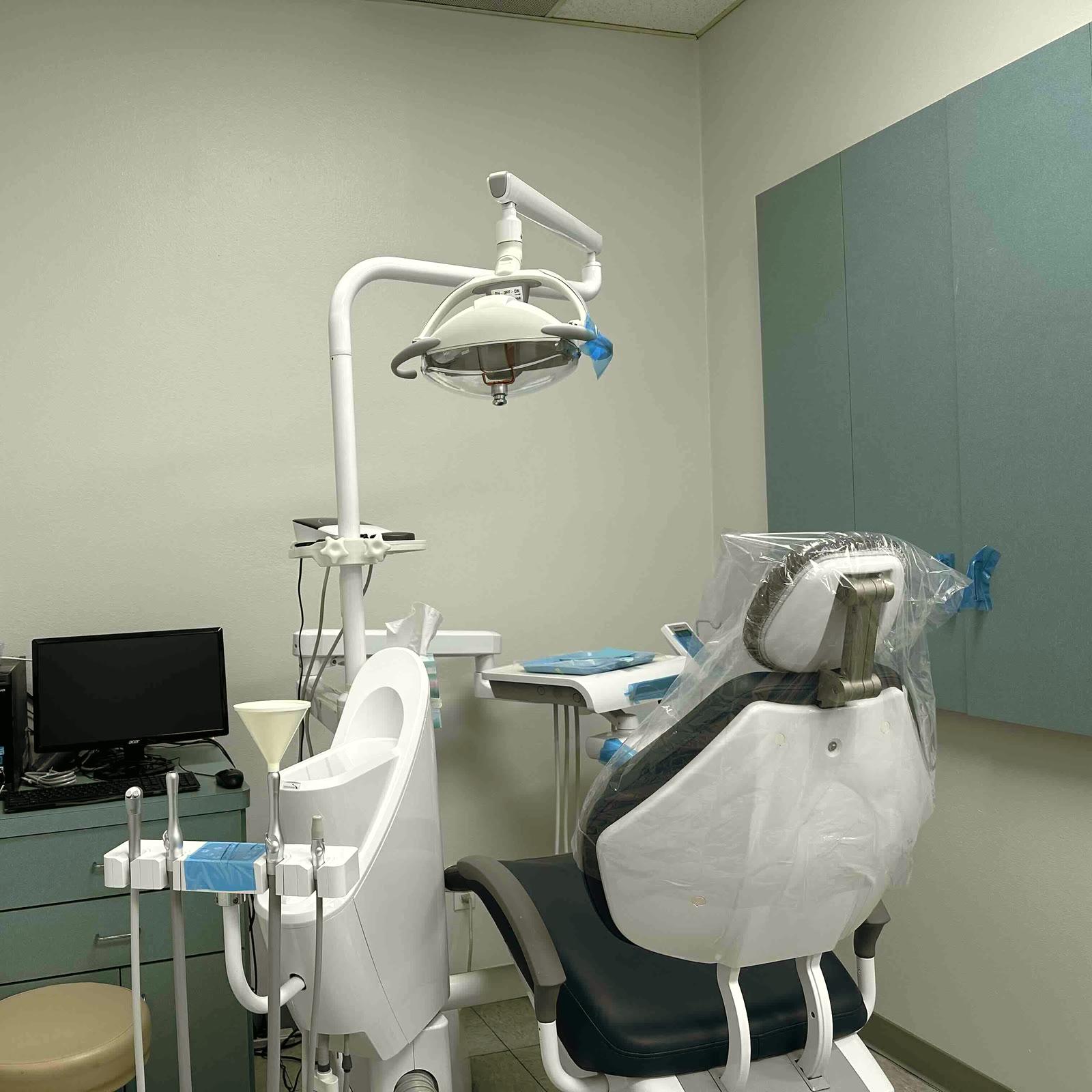 Una sala de tratamiento de la clínica en Temple City: un sillón dental junto a una pared verde azulada, con la lámpara y el instrumental listos para la siguiente visita